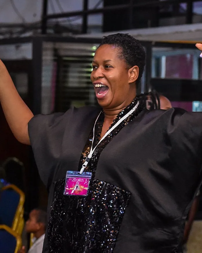 A woman laughing and dancing with her arms flung wide at the King’s Daughters Conference